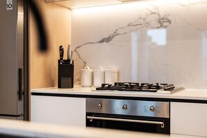 A modern kitchen with a built-in gas stove, stainless steel appliances, and a marble backsplash. - StayCentral - Boulevard Gardens (Coburg) - Sacramento Way, Coburg - 3 Bedrooms, 4 Beds, 2 Bathrooms, 2 secure undercover parking spots. (Coburg)