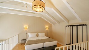 A bedroom with a bed, two wall-mounted lights, a hanging light fixture, a small side table, and a staircase. - Brilliant Duplex Studio w/ Balcony for 3 in Center (Oporto)