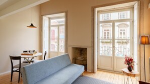 A room with a sofa, a table with a tray, a vase with flowers, and a fireplace. - Brilliant Duplex Studio w/ Balcony for 3 in Center (Oporto)