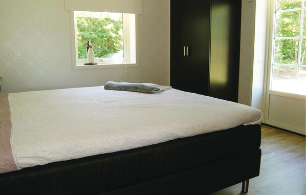 Un dormitorio con una cama grande, una ventana y un armario oscuro.