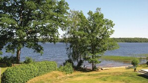 Vista de un lago con zona verde, árboles y un muelle.