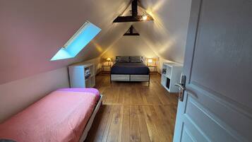 A bedroom with a sloped ceiling, a bed, bedside tables, a wardrobe, and a skylight.