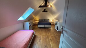 Un dormitorio con techo inclinado, una cama, mesitas de noche, un armario y un tragaluz.