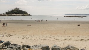 Une plage avec un château perché sur une colline en arrière-plan.