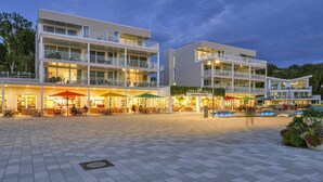A multi-story hotel with outdoor seating areas and a covered walkway. - Dünenvilla Comfort (Lübeck)