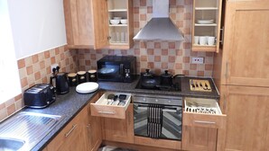 A compact kitchen with wooden cabinets, a microwave, a stove, and a toaster. - Beautiful 2-bed Apartment in Poulton-le-fylde (Poulton-le-Fylde)