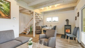 Un salon moderne avec un escalier, un coin repas et un poêle à bois.