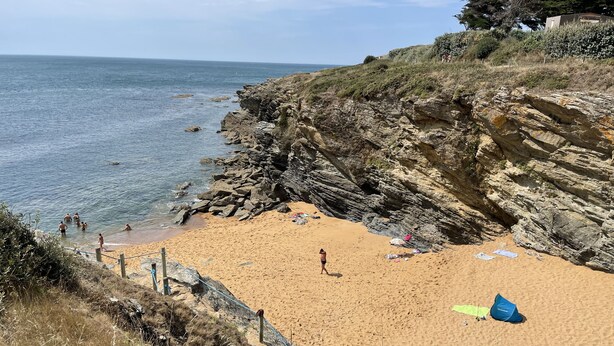 A beach with rocky cliffs, clear blue sea, and a few people enjoying the water. - Rare! Seafront vacation home with direct access to sea and beach (Pornic)