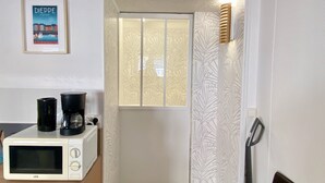 Une petite cuisine équipée d’un four à micro-ondes, d’une machine à café et d’une petite fenêtre.