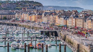 Un port avec des bateaux, un château et des bâtiments le long de la rive.