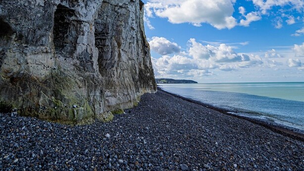 Une côte rocheuse avec une falaise abrupte et une plage de galets.