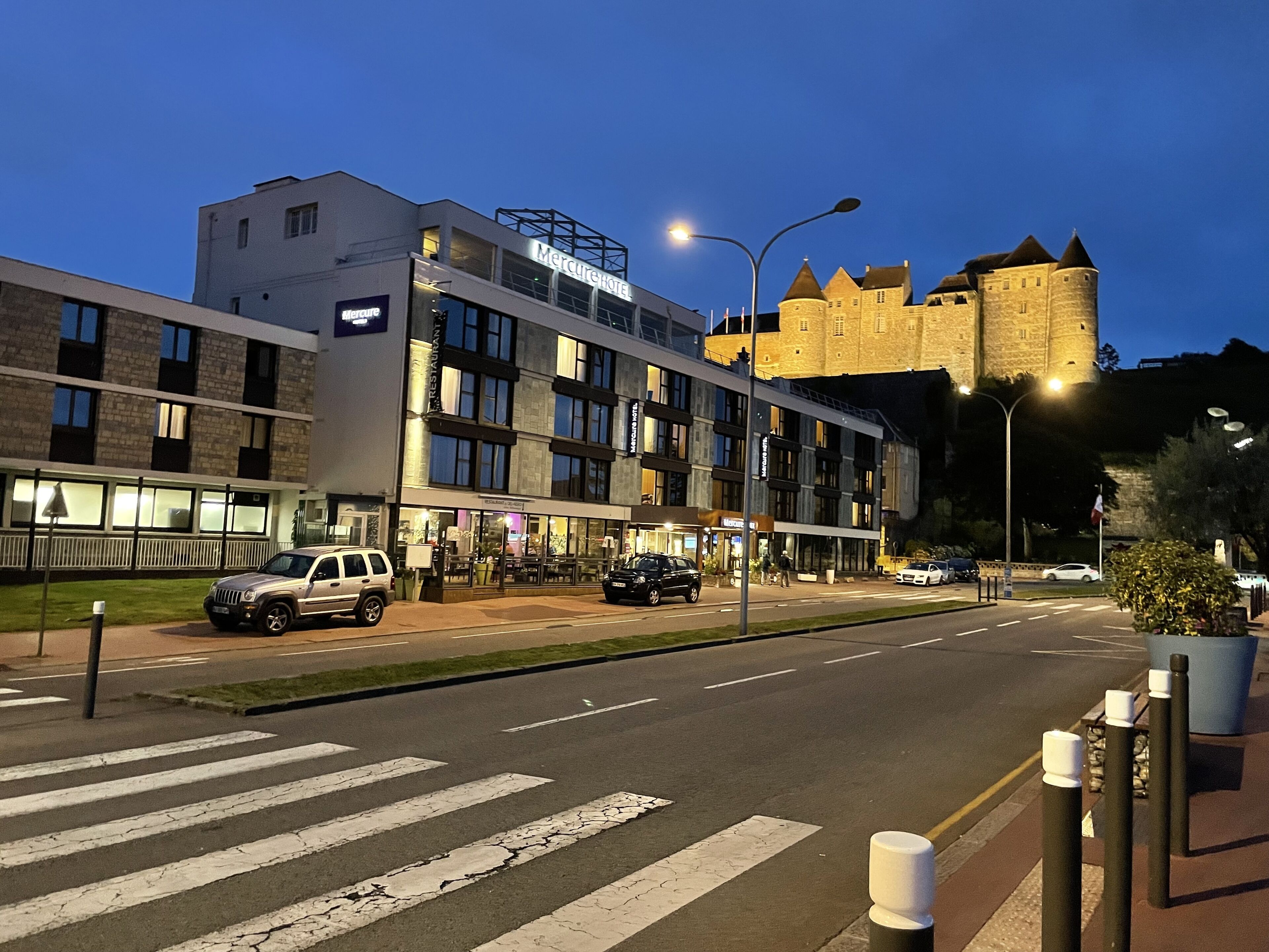 Een hotel met een modern gebouw en een historisch kasteel op de achtergrond.
