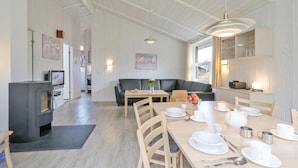Un coin repas avec une table en bois dressée pour quatre personnes, un canapé et un téléviseur en arrière-plan.