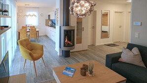 A modern living room with a sofa, a yellow chair, a coffee table with a book and candles, and a fireplace.