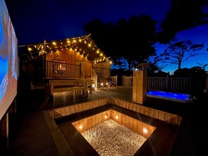 A wooden deck with a hot tub, string lights, and a seating area. - Aladdin Safari Tent (Tenby)