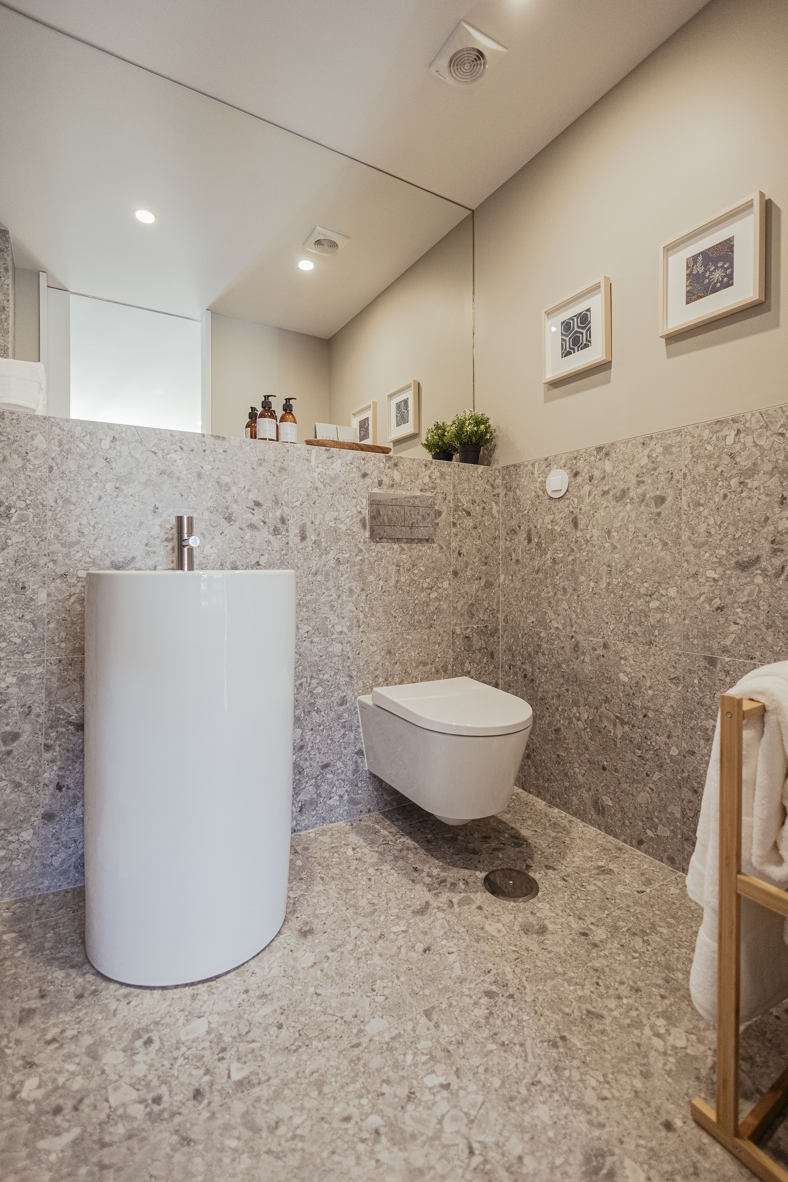 Une salle de bain moderne avec un grand lavabo blanc, des toilettes et un mur en marbre.
