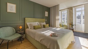 Una camera da letto con un letto, una sedia, un comodino con una lampada e una finestra con tende.