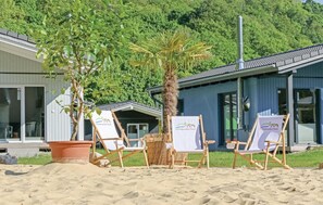 A beachside property with a wooden deck, beach chairs, and a palm tree. - Ferienhausdorf Thale (Thale)