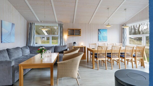 A cozy room with a sofa, dining table, wicker chairs, and a small round table. - Morgensonne 6 - Dorf 2 (Lübeck)