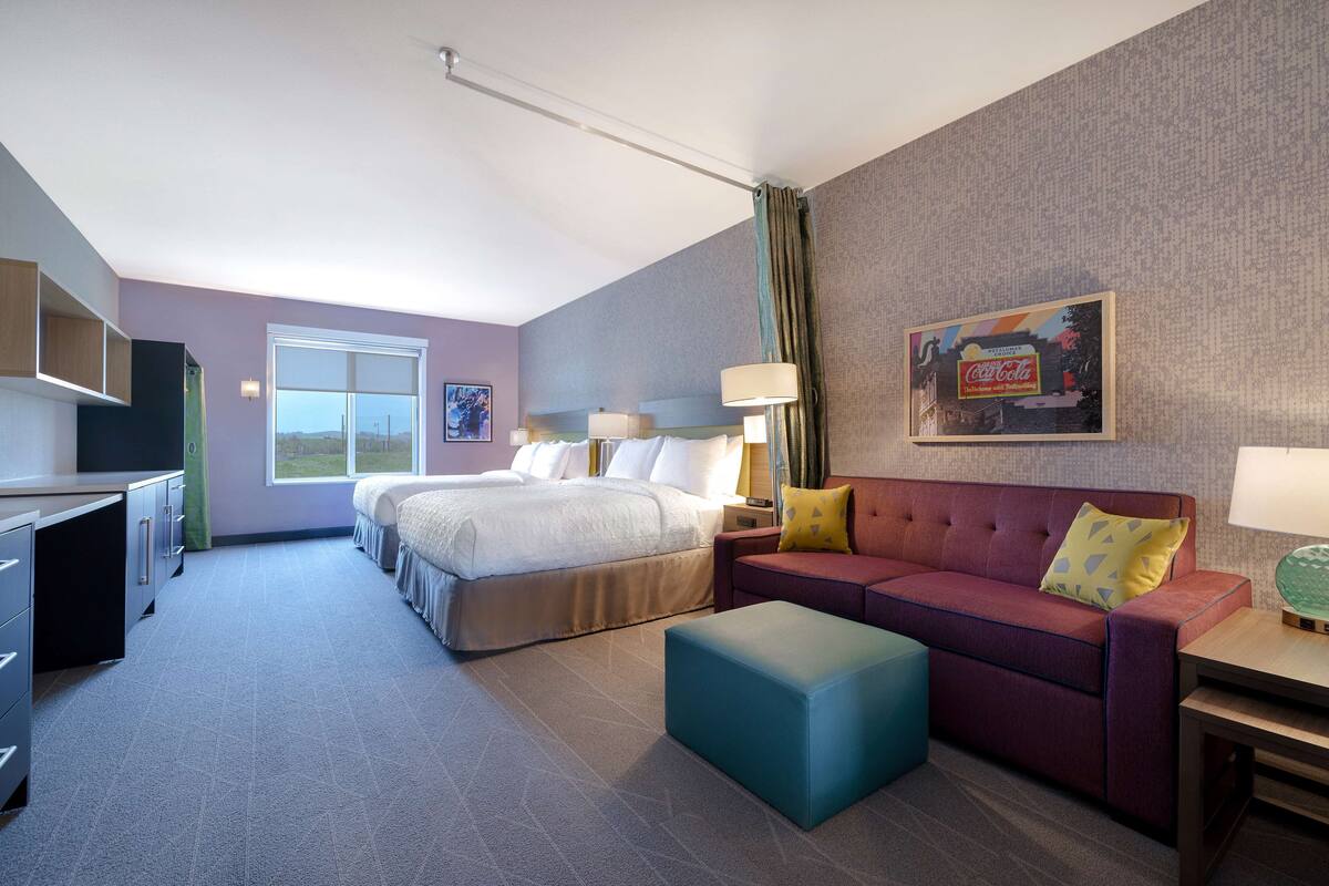 A hotel room with a bed, a sofa, a desk, and a window.