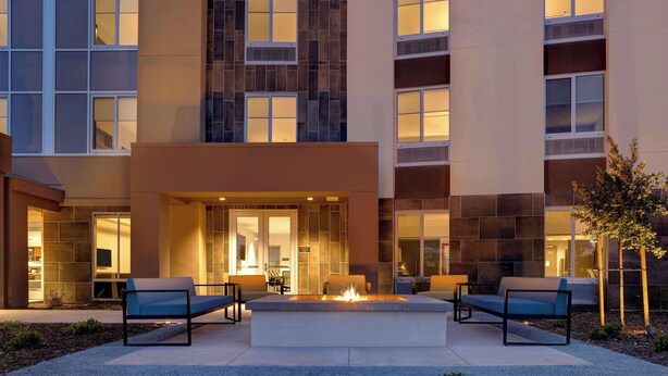A modern building with a courtyard featuring a fire pit and seating.