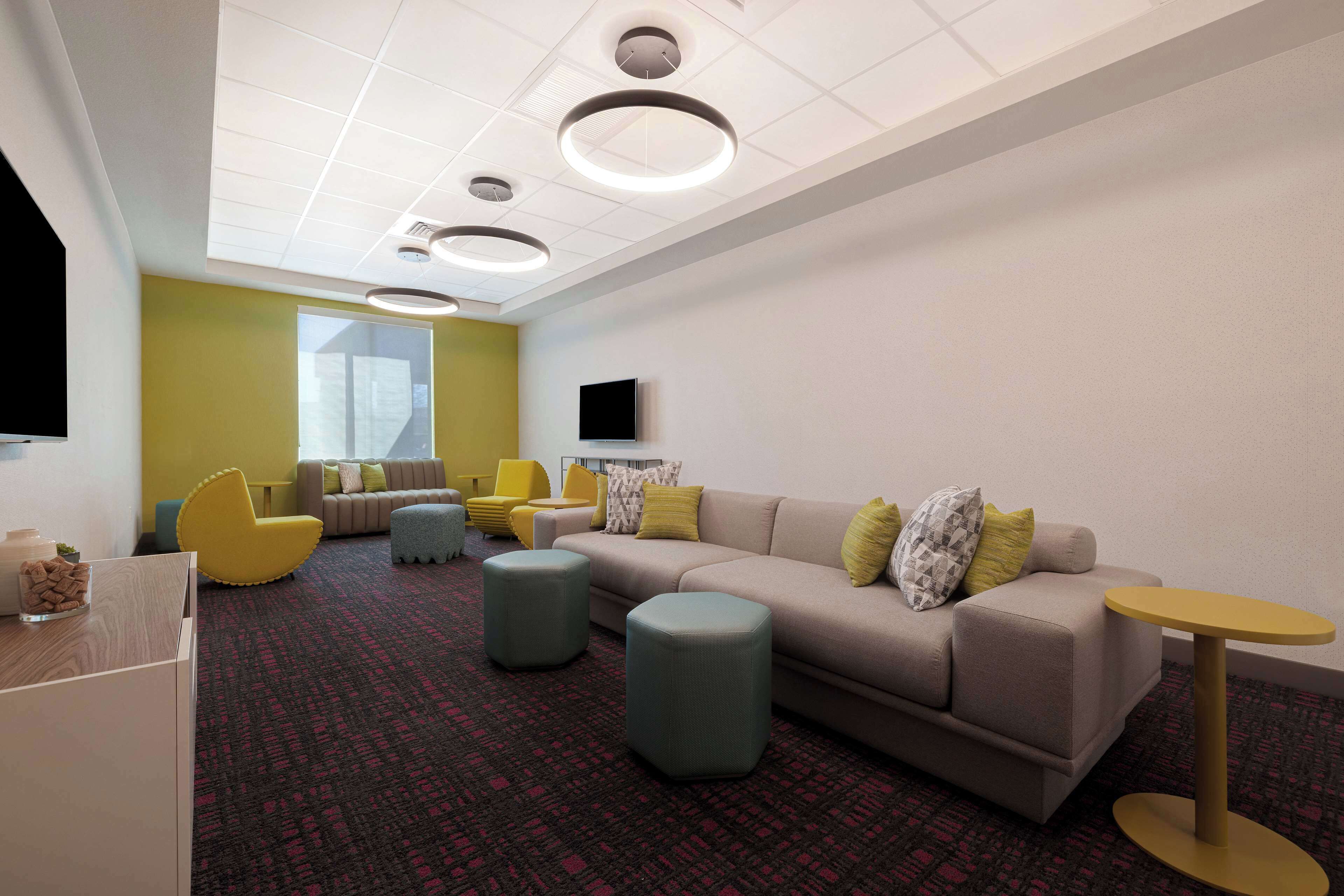 A modern lounge area with a sofa, ottomans, and a small table.