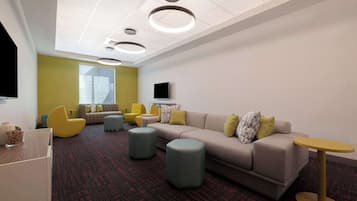 A modern lounge area with a sofa, ottomans, and a small table.