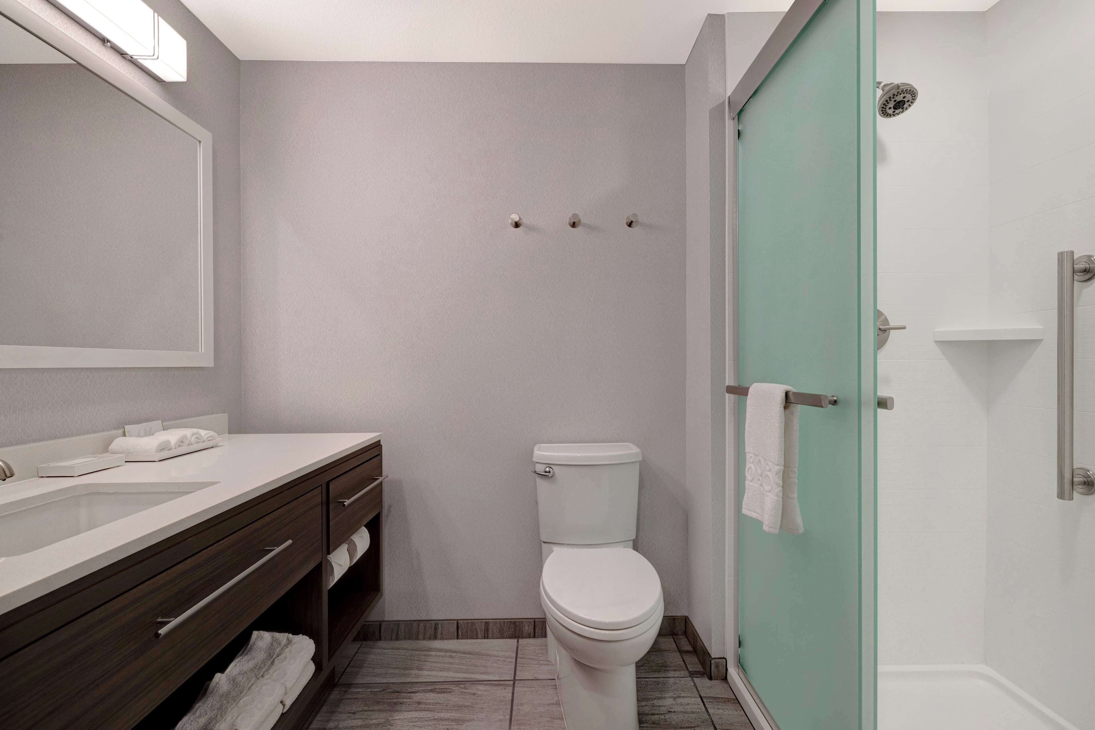A modern bathroom with a white toilet, a sink with a mirror, and a glass shower enclosure.