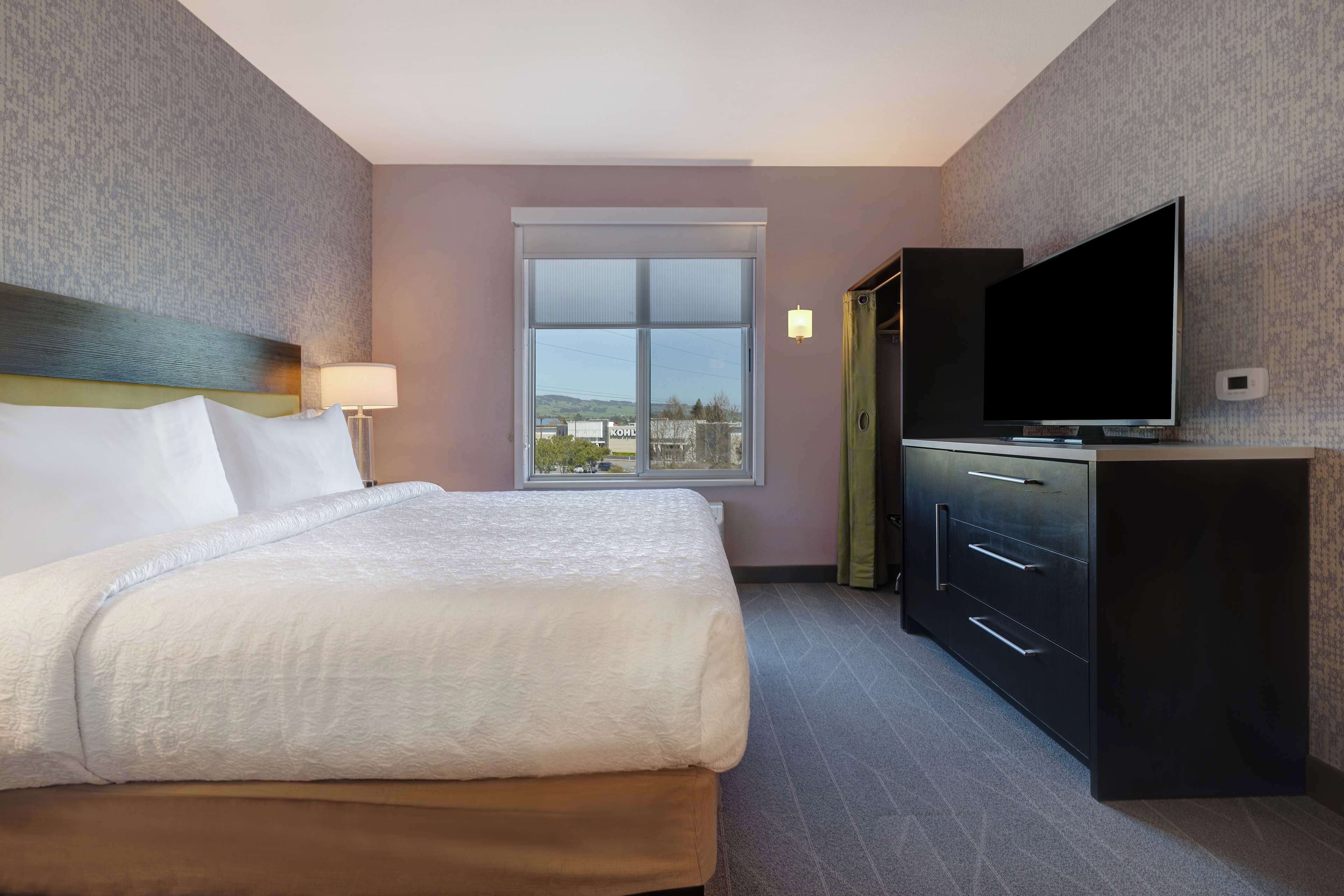 Een hotelkamer met een bed, een televisie, een raam en een bureau.