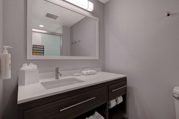 A modern bathroom with a large mirror, a sink, a dark wooden vanity, and a toilet. - Home2 Suites by Hilton Petaluma (Petaluma)