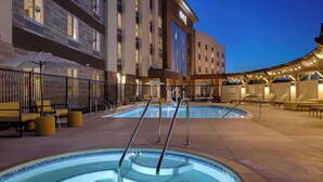 A hotel with a swimming pool, outdoor seating, and a covered area with umbrellas.