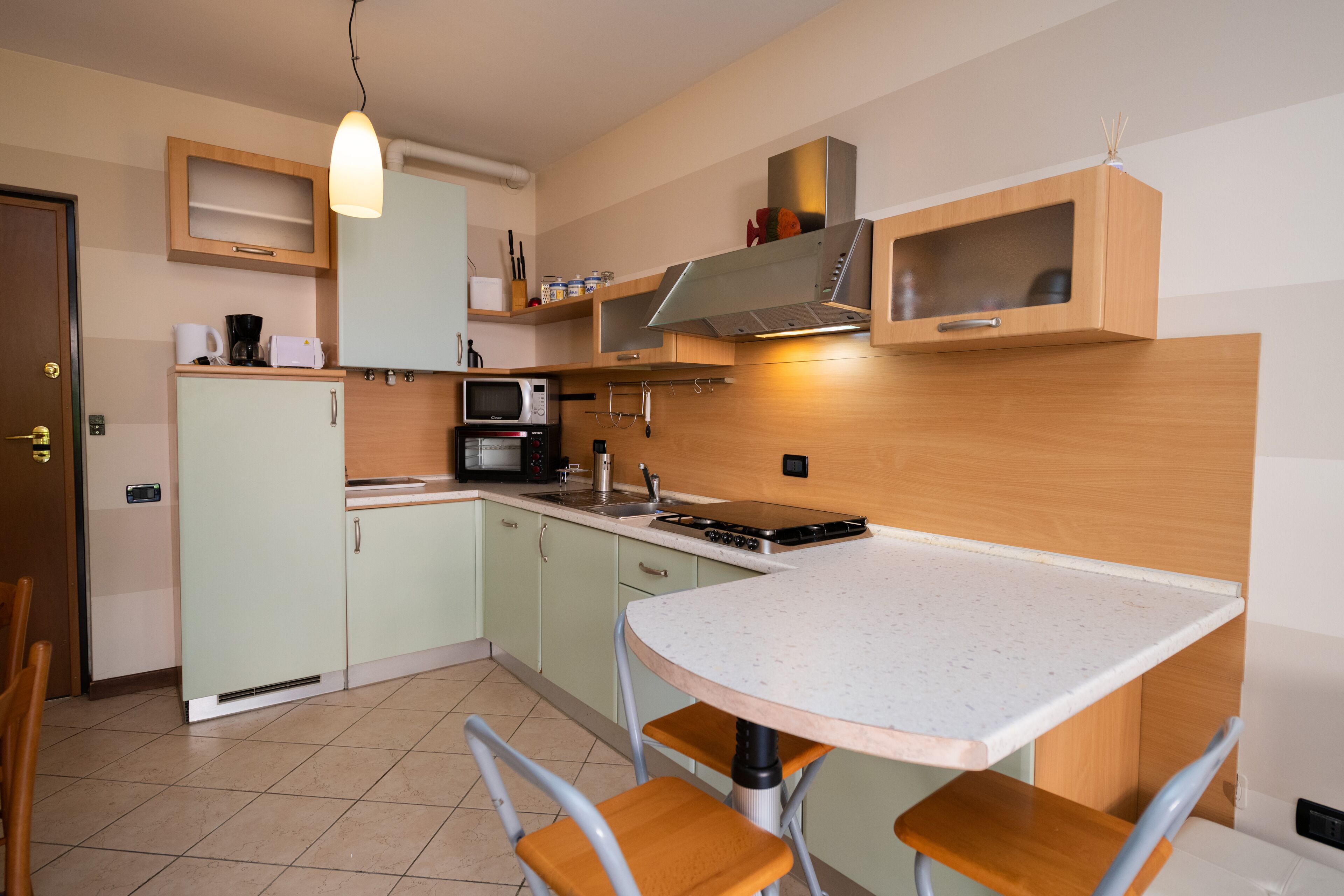 A compact kitchen with a microwave, stove, and cabinets. There is a dining table with chairs.