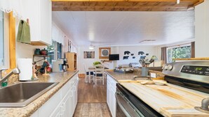 A modern kitchen with granite countertops, white cabinetry, a wooden floor, and a large stove. - Cabin in the forest, close to Bass Lake & Yosemite, mountain views & deck (Oakhurst)