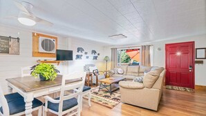 A cozy living room with a dining area, a red door, and a large window with curtains. - Cabin in the forest, close to Bass Lake & Yosemite, mountain views & deck (Oakhurst)