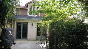 A house with a paved driveway leading to a front door, surrounded by greenery. - Nice, friendly house near Paris (Argenteuil)
