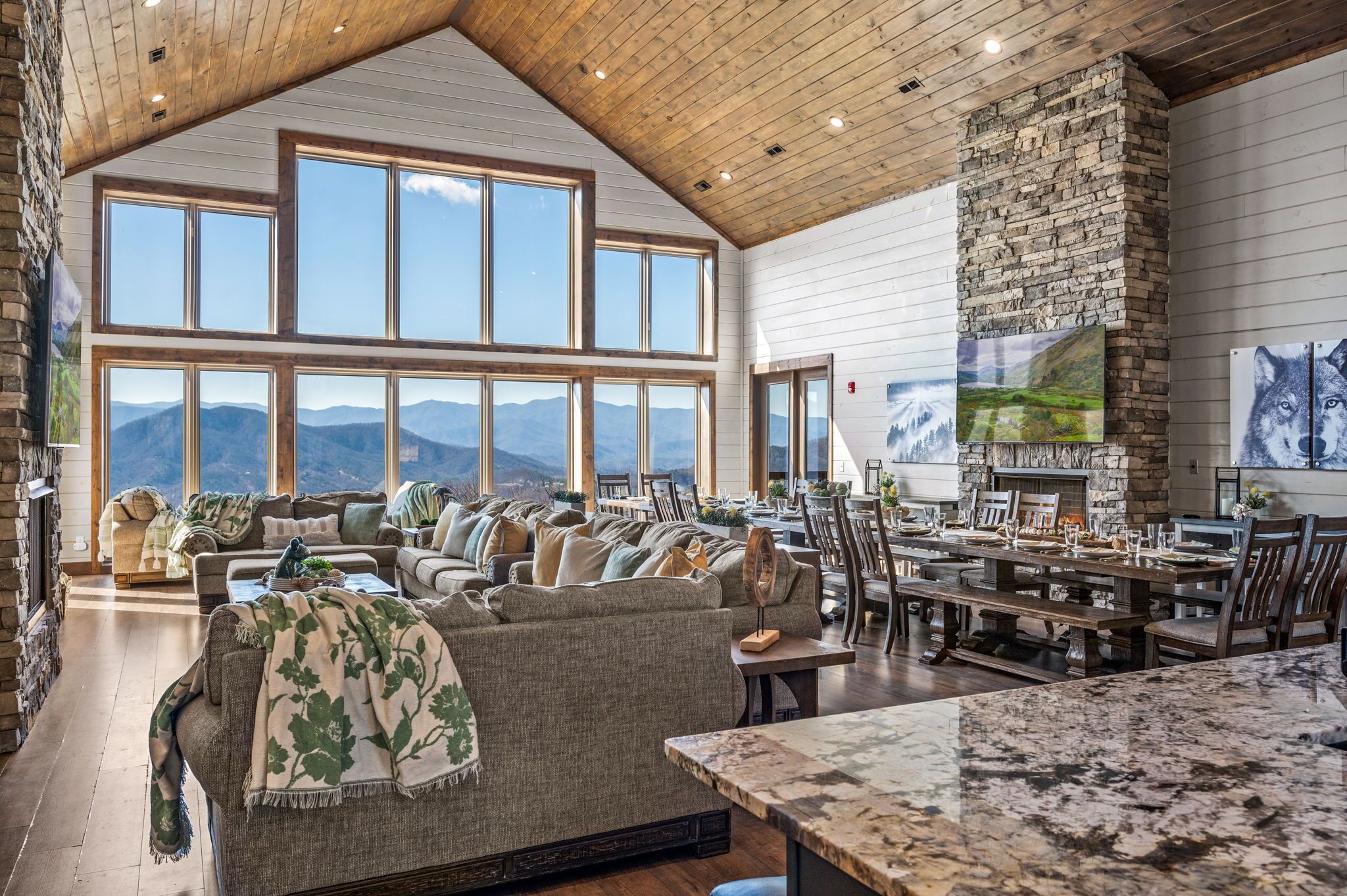 A spacious living area with a fireplace, large windows, and a view of mountains.