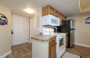A compact kitchen with white cabinets, a microwave, a refrigerator, and a stove. - Welcome to Beach Life! 106 South Point " traffic free beach" (Ponce Inlet)