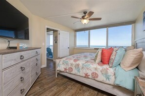 A bedroom with a bed, a ceiling fan, a dresser, and a window with a view of the ocean. - Welcome to Beach Life! 106 South Point " traffic free beach" (Ponce Inlet)