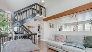 A spacious living room with a wooden staircase, a grey sofa, and a large window with blinds. - 6 Mi to Dtwn: Arvada Home w/ Hot Tub & Yard (Arvada)