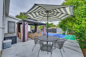 A patio with a round table and chairs, a striped umbrella, and a covered seating area. - Walk to Poway Farmers' Market: Family Retreat! (Poway)