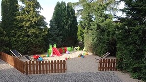 Un parque infantil con un tobogán y estructuras para escalar, rodeado de árboles.