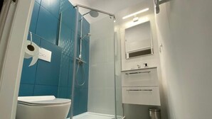 A modern bathroom with a glass-enclosed shower, a white toilet, and a small sink with a mirror above it. - Appartment B1 Sarbinowo, 200 m vom Strand und Centrum (Sarbinowo)