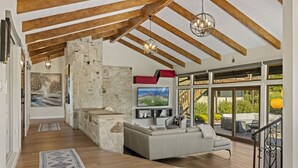 Ampla sala de estar com lareira de pedra, uma televisão grande e vista para o exterior.