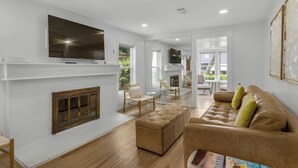 A modern living room with a fireplace, a flat-screen TV mounted above it, and a comfortable seating area with a sofa and armchairs. - Private Pool & Feet to the Beach, Near to Chiringo & Red Bar + Free Tickets! (Santa Rosa Beach)