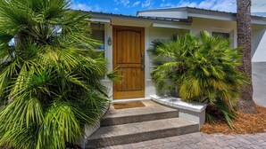 A house with a wooden front door, a small porch, and steps leading to the entrance. - Private Pool & Feet to the Beach, Near to Chiringo & Red Bar + Free Tickets! (Santa Rosa Beach)