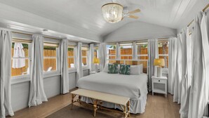 A bedroom with a large bed, a bench, two bedside tables, a ceiling fan, and windows with curtains. - Private Pool & Feet to the Beach, Near to Chiringo & Red Bar + Free Tickets! (Santa Rosa Beach)