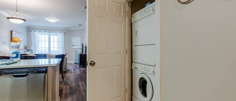 A compact kitchen with a dishwasher, a washing machine, and a dining area with a table and chairs.