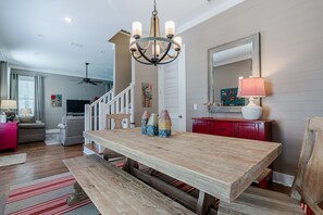 A spacious living area with a wooden dining table, a chandelier, and a red cabinet.