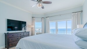 A bedroom with a large bed, a ceiling fan, a TV on a dresser, and a view of the ocean. - Gulf-Front, Lovely Views & Private Beach, Sleeps 12 + Free Attraction Tickets (Seagrove Beach)