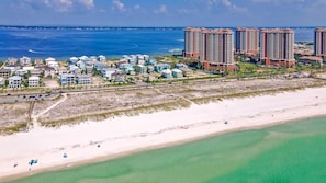A coastal area with a beach, a road, and several high-rise buildings.